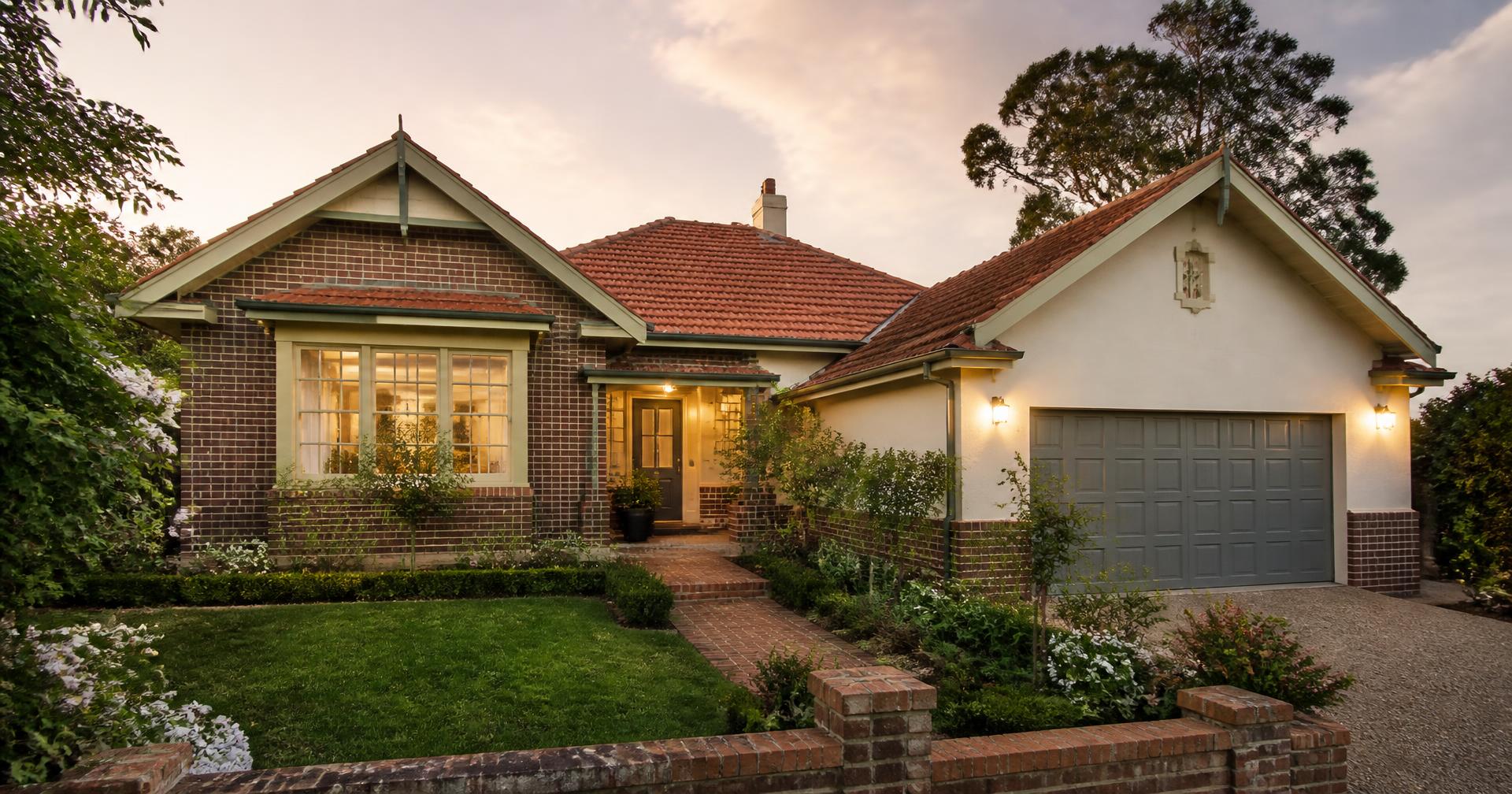Established Sydney home with a garden path and warm interior lighting at dusk