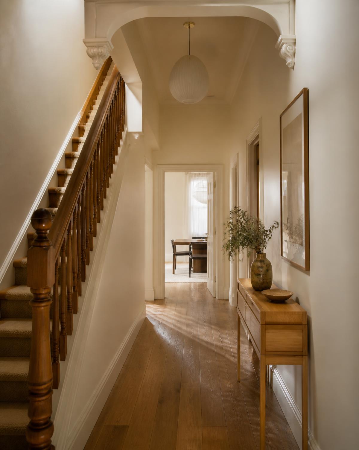 Quiet entry hallway with timber staircase and soft afternoon light in a Sydney home