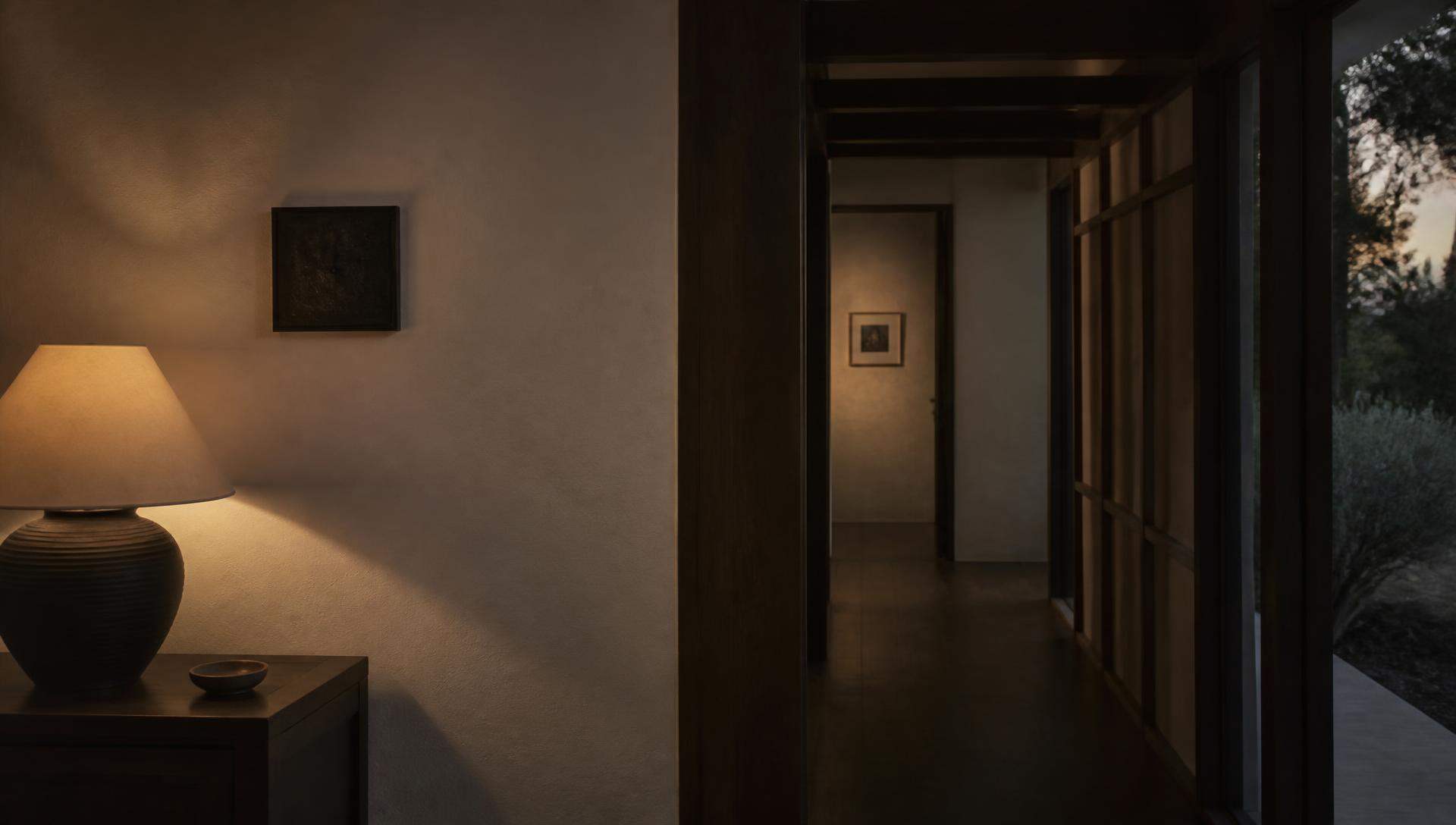 Softly lit hallway at dusk in an Australian home, with plaster walls and dark timber joinery